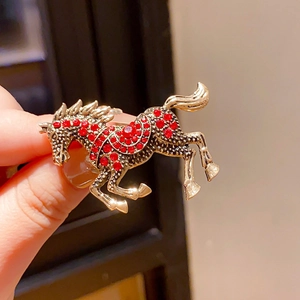 Detail of running horse brooch with red rhinestones and vintage gold metal finish