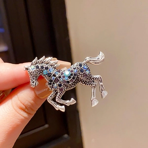 Detail of a vintage horse brooch featuring colorful rhinestones on a silver base