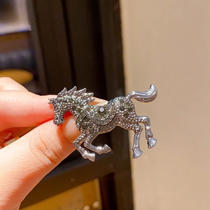 Detailed view of horse-shaped brooch with dark rhinestones on silver-tone metal alloy