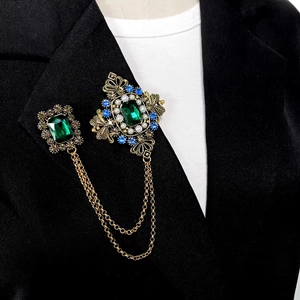Broche rétro à l'émeraude avec chaînes dorées sur le revers d'un costume noir