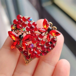 Detail shot of a vintage heart brooch with red crystals and butterfly elements
