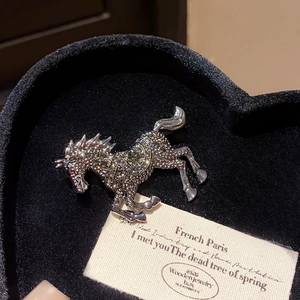 Close-up of sparkling rhinestone horse brooch resting in a black heart-shaped gift box