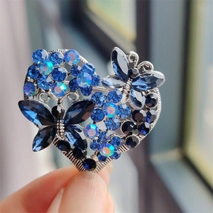 Detailed close-up of blue rhinestone heart brooch with butterfly and floral elements