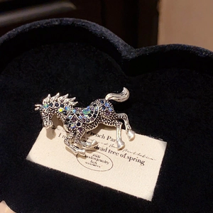 Macro shot of vintage horse brooch with blue and purple crystals on black velvet box