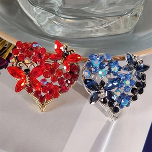 Close-up of vintage heart brooches with rhinestones and butterfly details in red and blue