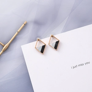 Detailed macro view of geometric diamond stud earrings with marble resin and gold frame