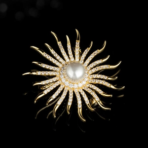 Elegante broche de girasol dorado con una perla blanca central y detalles en circón