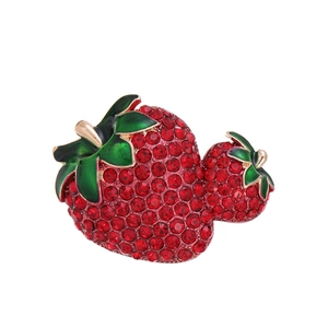 Macro detail of double strawberry brooch featuring red rhinestones and green leaves