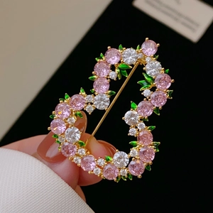 Dettaglio della spilla a cuore in zircone rosa con foglie di smalto verde su base scura
