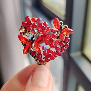 Macro detail of luxury red heart brooch with crystal butterfly wings in gold setting