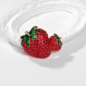 Macro shot of twin strawberry brooch with red rhinestones and green enamel details