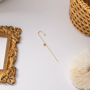 Detailed close-up of a gold-finish ear cuff featuring a clear sparkling cubic zirconia stone