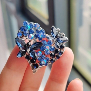 Detailed macro view of heart brooch with blue and black crystals and butterfly motifs