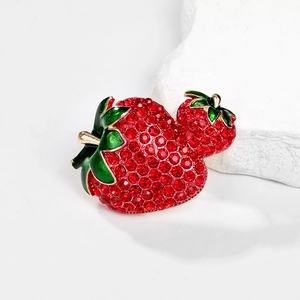Macro detail of alloy strawberry brooch featuring red crystals and green enamel leaves