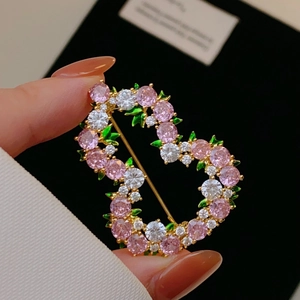 Dettaglio macro di spilla a forma di cuore con zirconi rosa e motivi floreali a foglia