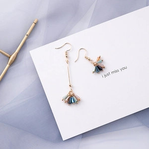 Detail view of gold asymmetrical earrings with multicolored blue beads on blue tulle