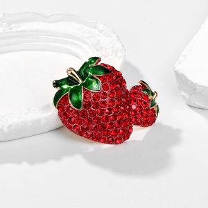 Detail shot of strawberry brooch with red rhinestones and green enamel leaves