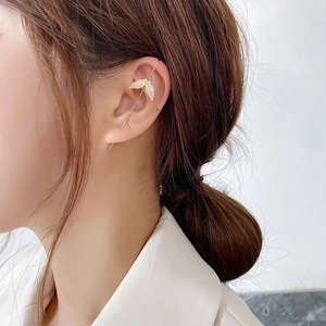 Detailed close-up of a sparkling gold fishtail ear crawler set with shiny zircons on ear