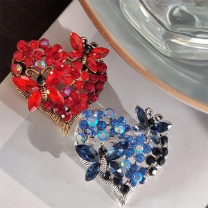 Close-up of luxury heart brooches with rhinestone butterfly patterns in red and blue