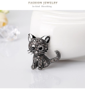Close-up of a vintage cat brooch with grey and black rhinestones on a silver base