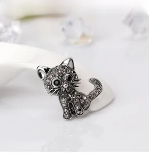 Detail of vintage cat brooch with grey crystals and black gem eyes on white ceramic
