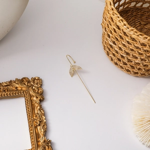 Detail shot of a golden fishtail ear cuff with micro-paved zircons in an elegant layout