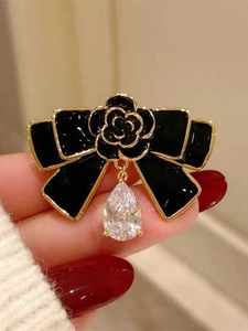 Vue macro détaillée de la broche nœud camélia noir avec pendentif en zircon goutte