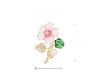 Détails de la broche fleur en émail avec pétales roses, perle et base en métal doré