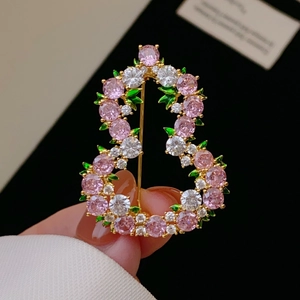Dettaglio della spilla da giardino elegante con zirconi rosa e foglie in smalto verde