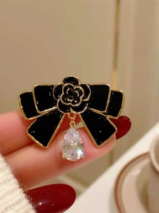 Vue détaillée d'une broche rétro française avec nœud en émail noir, camélia et cristal