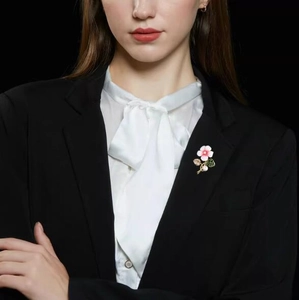 Détail d'une broche fleur rose avec perles sur le revers d'un blazer noir chic