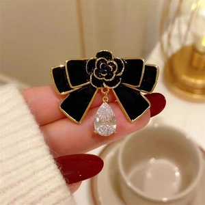 Détail d'une broche nœud vintage avec fleur de camélia et un strass en forme de poire