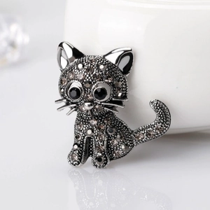 Retro cartoon cat brooch with grey rhinestones and black gem eyes on white background