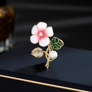 Broche fleur dorée élégante avec émail, strass et perle sur un coffret à bijoux bleu