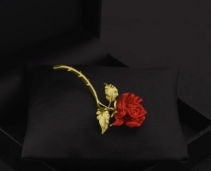 Detailed macro view of the romantic red rose brooch with matte gold leaves and stems