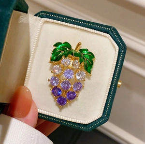 Exquise broche de raisin violette avec base dorée et cristaux colorés dans une boîte
