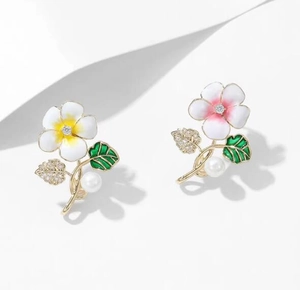 Détail macro de boucles d'oreilles fleurs en émail avec feuilles en zircon et perles
