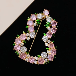Elegant gold heart-shaped brooch featuring pink and white zircons with green leaf accents
