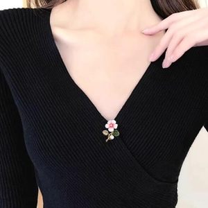 Broche fleur en émail rose avec feuilles vertes et perle sur un pull noir élégant