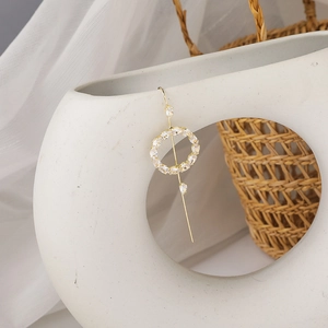 Detailed close-up of a gold zircon earring hanging on a white ceramic vase with soft lighting