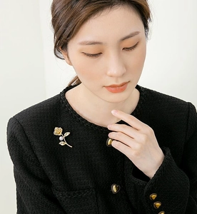 Detail of elegant gold rose brooch with white pearl on a black tweed jacket lapel