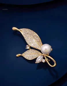 Gros plan détaillé d'une broche en forme de feuille avec zircons et perle blanche élégante