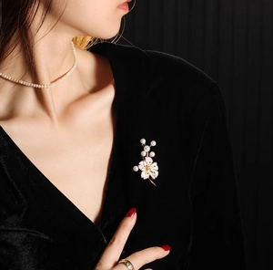 Broche fleur en émail rose et perle blanche sur une robe en velours noir pour un style élégant