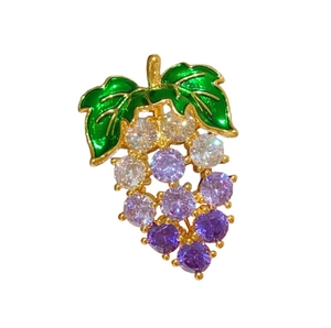 Détail de la broche raisin avec pierres de zircone violettes et feuilles d'émail vert