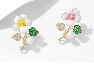 Détail de la broche fleur en émail avec pétales blancs, feuilles vertes et perles blanches