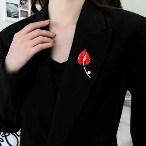 Detailed close-up of Calla Lily brooch with red petals and pearl on a black suit jacket