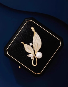 Détail d'une broche feuille élégante avec cristaux scintillants et perle blanche