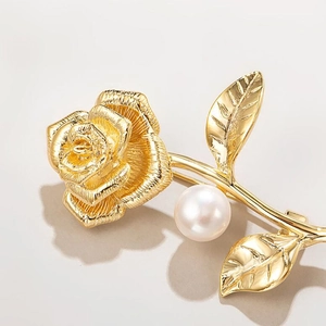 Detailed macro view of golden metal rose brooch with silk texture and pearl accent
