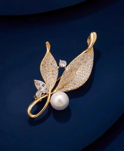 Vue détaillée de l'élégante broche feuille d'or avec perle et cristaux scintillants