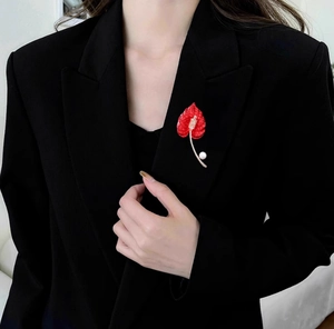 Detailed close-up of a luxury red flamingo lily brooch with pearls on a black suit jacket